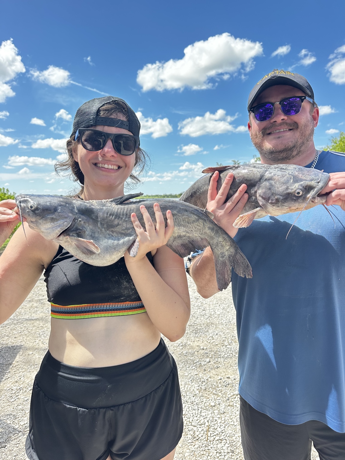 Paige and Charles grinning with their fishing catches